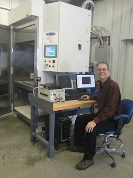 Gary Delserro sits at his lab’s Highly Accelerated Life Test (HALT) Chamber, which performs combined temperature and vibration loads simultaneously.